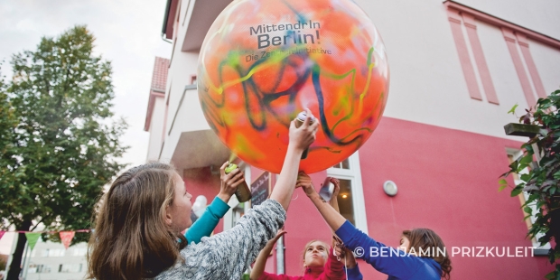 Drei Linder halten einen Ballon mit der Aufschrift 